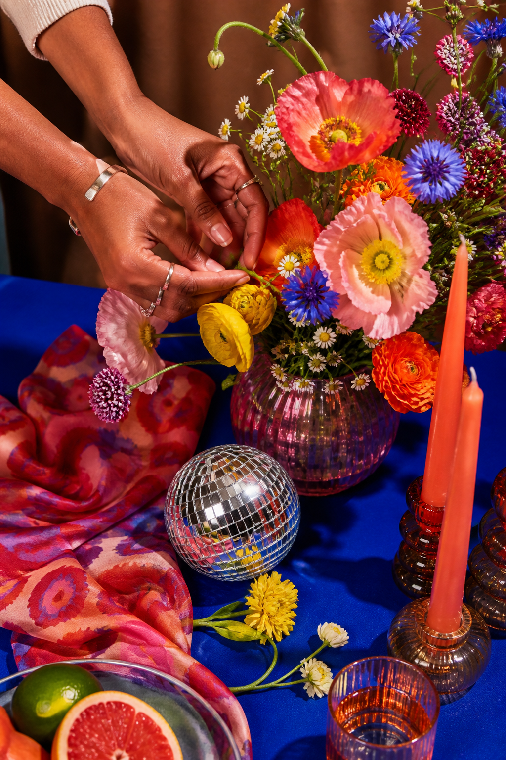 Hands arranging flowers, candles and a disco ball for an event